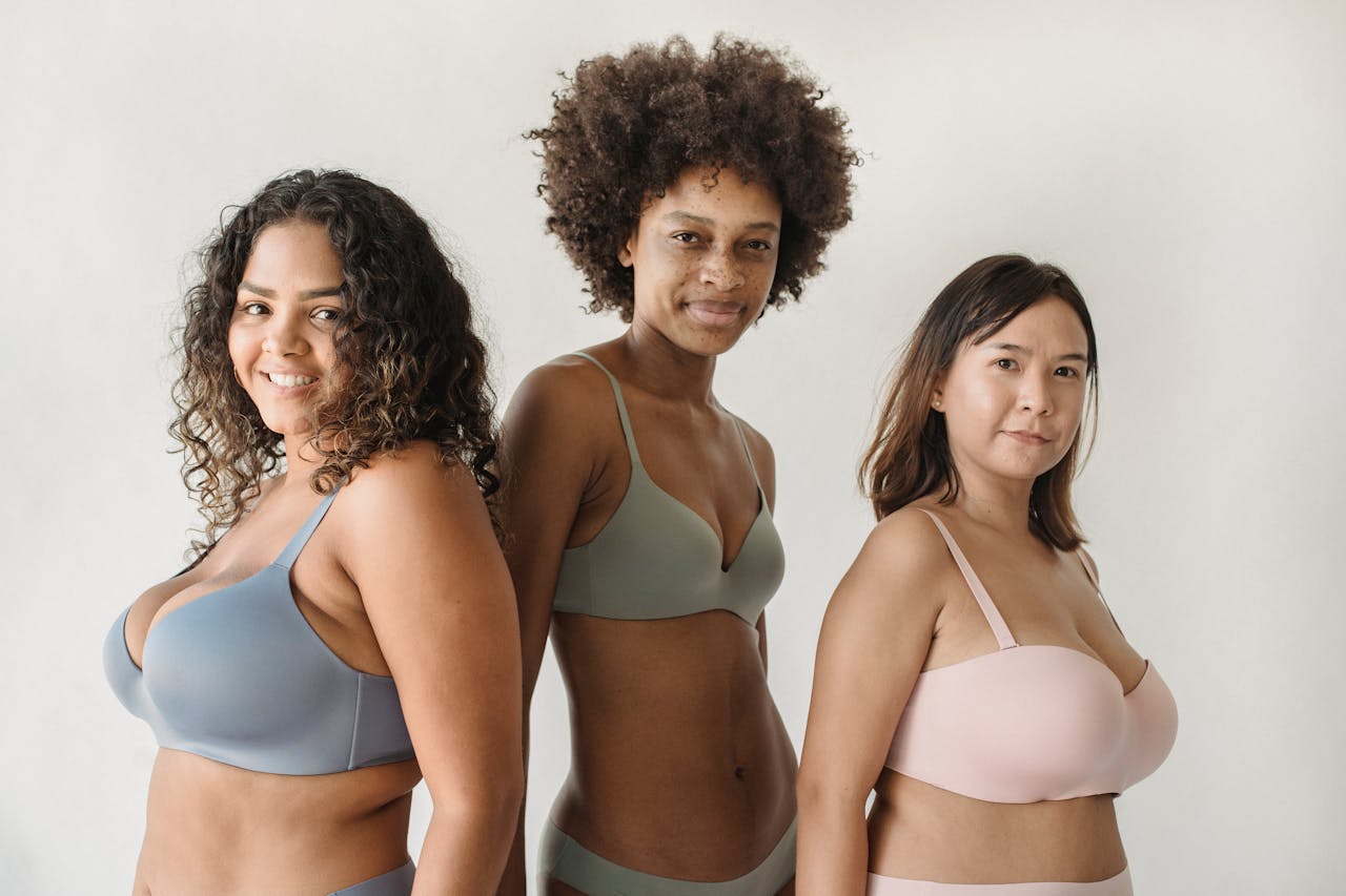 pexels-photo-5253433 Three diverse women in bras smiling confidently while standing indoors.